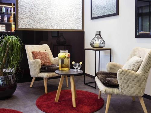 a living room with two chairs and a table with a drink on it at Aparthotel Adagio Genève Mont-Blanc in Geneva