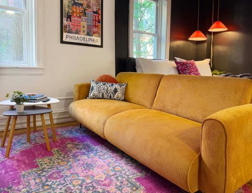 a brown couch in a living room with a table at Fifa Walkable King Bed Full Kitchen Central Apartment in Philadelphia