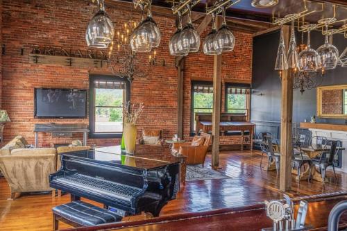 a living room with a piano and a brick wall at Brick Loft Penthouse on Main in Brevard