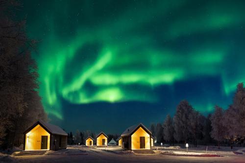 a group of cabanas under the aurora in the sky at Nilimella Camping & Resort in Sodankylä