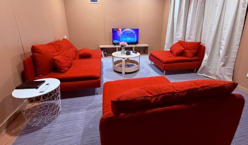 a living room with two red couches and a tv at Cabin 6- Snowy Accommodation in Adaminaby
