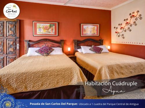 two beds in a room with orange walls at Posada de San Carlos del Parque in Antigua Guatemala