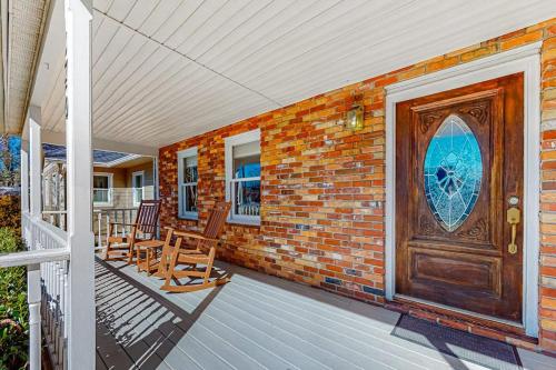 a brick house with a wooden door and chairs on a porch at Brevard Bungalow in Brevard