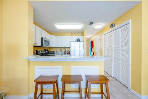 a kitchen with three wooden stools at a counter at The Dunes 503 in Gulf Shores