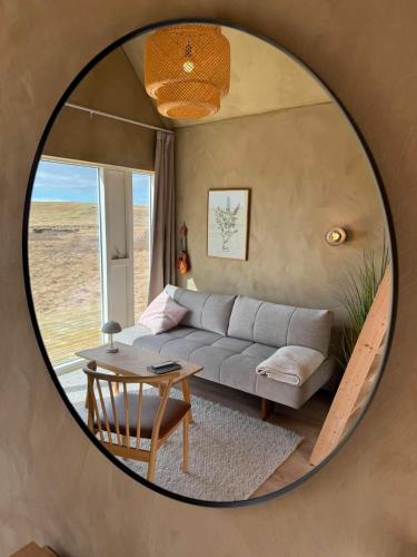 a mirror in a living room with a couch and a table at Cozy cottage with a view in Hella
