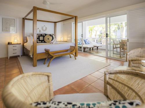 a bedroom with a bed and chairs and a patio at The Reef House Adults Retreat - Enjoy 28 Complimentary Inclusions in Palm Cove