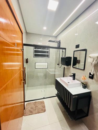 a bathroom with a glass shower and a sink at Hostel Pouso Gru - Translado Aeroporto Gru grátis in Guarulhos