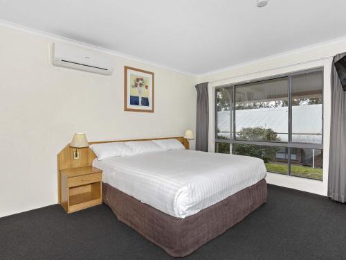 a bedroom with a bed and a large window at ibis Styles Canberra Eagle Hawk in Canberra