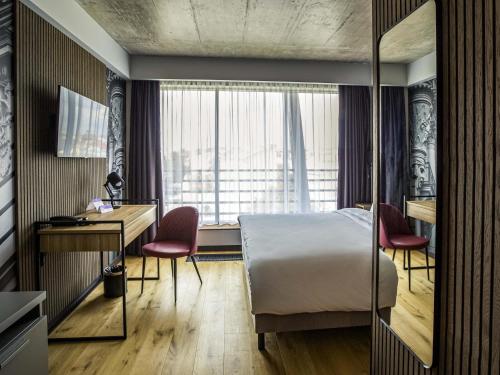 a bedroom with a bed and a desk and a window at Mercure Riga Centre in Riga