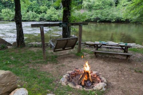 a fire pit with a picnic table next to a river at Above the River in Sylva