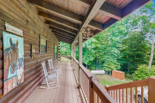 a porch of a wooden cabin with chairs on it at Walela Cabin in Topton