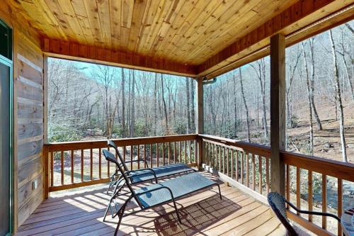 a screened in porch with a bench and chairs on it at The Rushing Creek Cabin in Topton