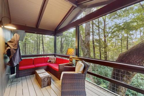 a screened in porch with a red couch and chairs at Campfire Hideaway in Highlands