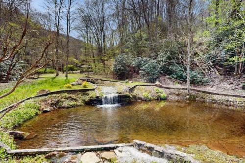 a pond with a waterfall in the middle of a forest at Creeksong Cabin in Topton