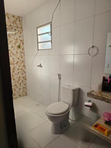 a white bathroom with a toilet and a window at Mirante in Crato