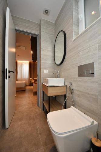 a bathroom with a sink and a toilet and a mirror at Giulia Center Hotel in Tirana