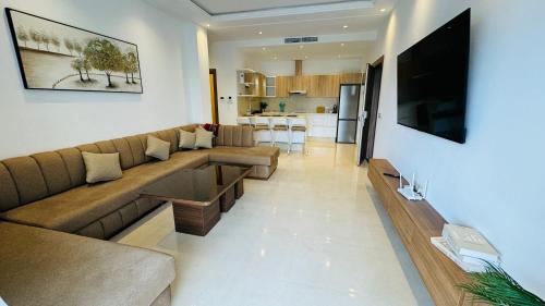 a living room with a brown couch and a kitchen at Les Jardins Bleus Pool - Martil in Martil
