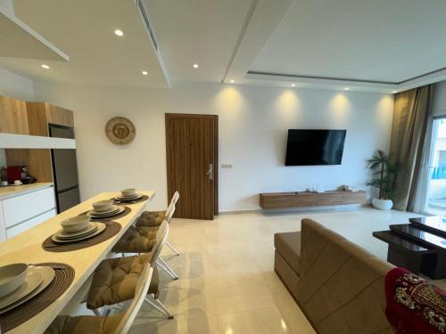 a kitchen and living room with a table and a couch at Les Jardins Bleus Pool - Martil in Martil