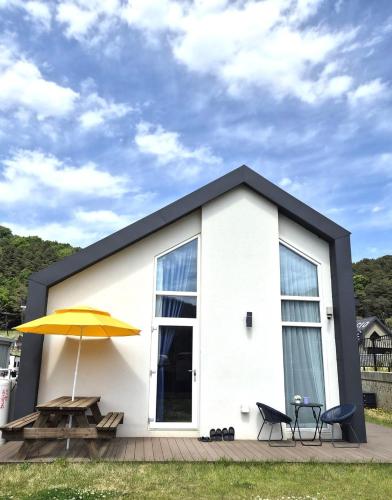 a white house with a table and a yellow umbrella at Paju Espacio Brillante in Paju