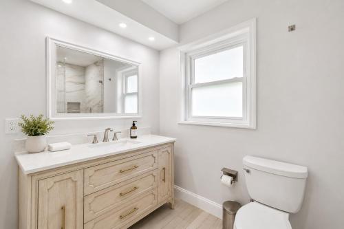 a bathroom with a toilet and a sink and a mirror at Tropical Dream - Pool - Firepit - Gazebo in Largo