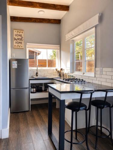 a kitchen with a refrigerator and a table with stools at Cabaña bosquepaz in Algarrobo