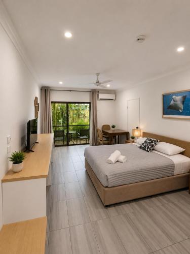 a bedroom with a bed and a desk and a television at Birch Resort Port Douglas in Port Douglas