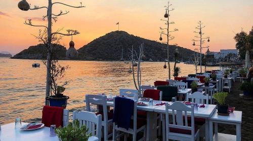 a group of tables and chairs on a beach with the ocean at My Marin Otel in Turgutreis