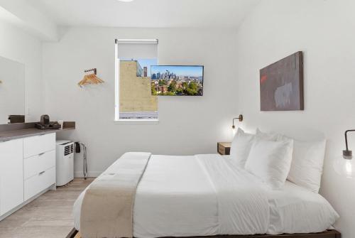 a white bedroom with a large bed with white pillows at The Boylston Hotel Capitol Hill in Seattle