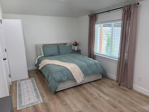 a bedroom with a bed with a green comforter and a window at Modern Private Studio - Separate Entry in Edgewood