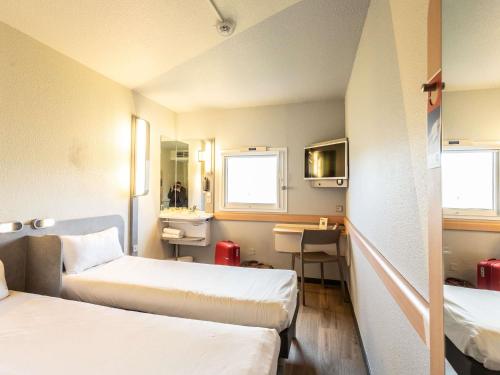a hotel room with two beds and a desk at ibis budget Bourges in Bourges
