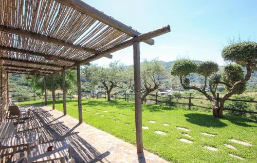 a pergola with benches and a field with trees at L'antica Pietra in Perdifumo