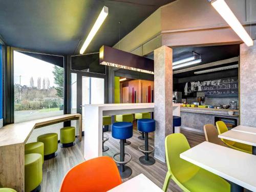 a restaurant with colorful chairs and tables and a counter at ibis Budget Caen Memorial in Caen