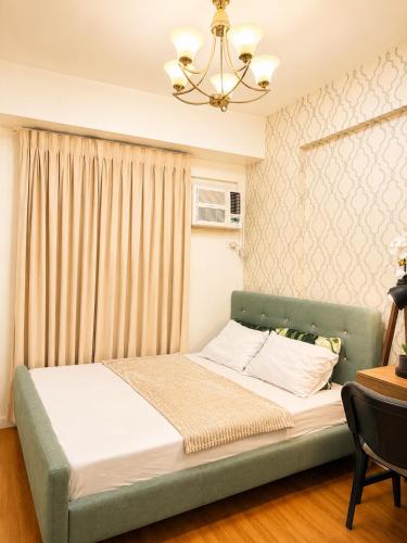 a bedroom with a green bed with a chandelier at Cityscape Suite in Davao City