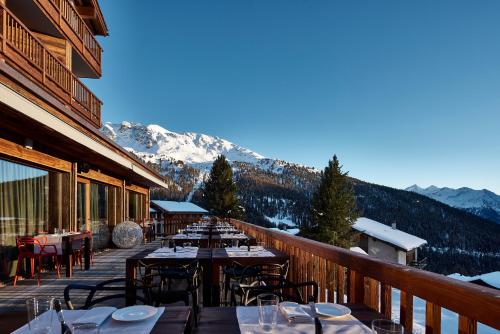 a restaurant with tables and chairs on a balcony at Chandolin Boutique Hotel in Chandolin