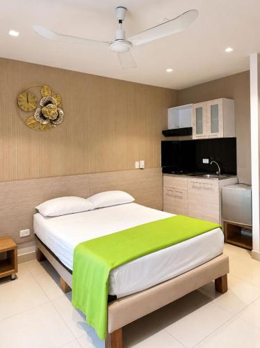 a bedroom with a large bed with a green blanket on it at Hotel Condina Pereira in Pereira