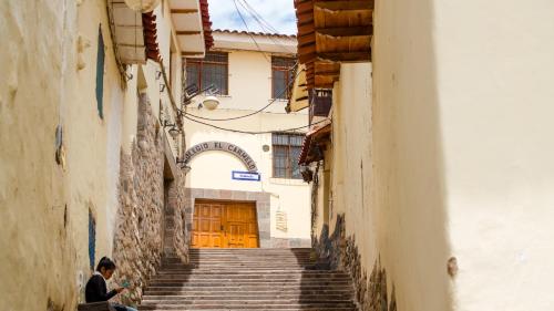 a man sitting on a stairs in an alley at Hosteria de Anita in Cusco