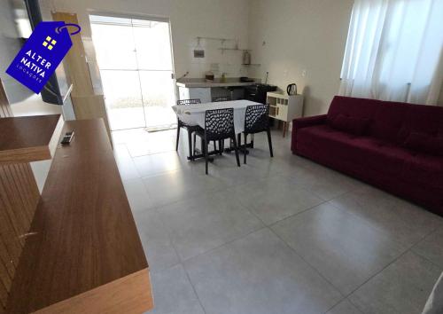 a living room with a red couch and a table at Casa Indaiá in Primavera do Leste