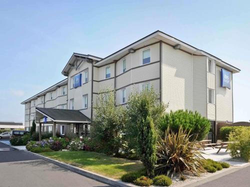 a large apartment building with a lot of plants at Ibis Budget Bayeux in Bayeux