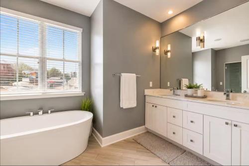 a bathroom with a tub and two sinks and a window at Family-Friendly 4BR Retreat Sleeps 12, Private Yard, Garage, Close to Stadiums, Casino & Downtown in Pittsburgh