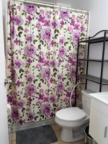 a bathroom with a floral shower curtain with a toilet at josedith'sweet house in Isabela