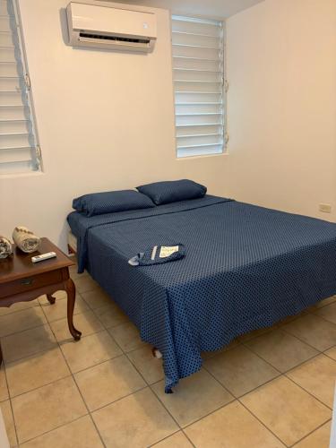 a bedroom with a bed with a blue bedspread and a table at josedith'sweet house in Isabela