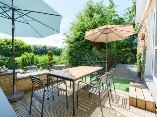 a patio with a table and chairs and an umbrella at Group Getaway in Amel in Amblève