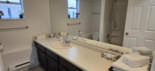 a white bathroom with a sink and a mirror at Bright 2 BR, Great Location in West Vancouver