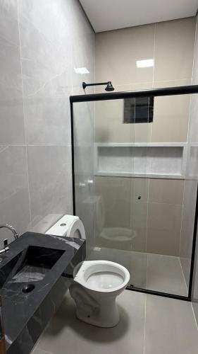 a bathroom with a toilet and a glass shower at Casa moderna próximo ao bumbodromo in Parintins