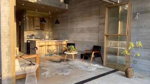 a living room with a table and a kitchen at CASA NU La Saladita surf point in Temalhuacán