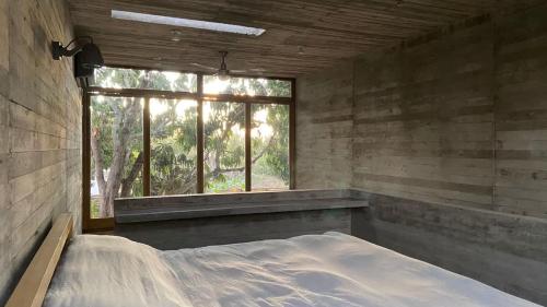 an empty room with a large window and a bed at CASA NU La Saladita surf point in Temalhuacán