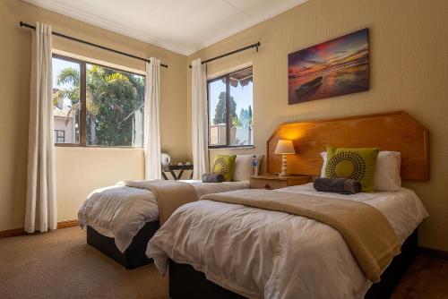 two beds in a room with two windows at The Bedford View Guest House in Germiston
