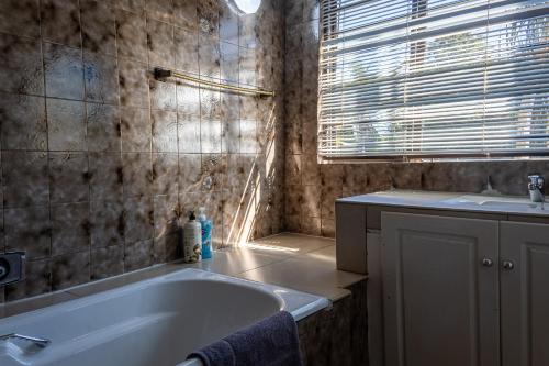 a bathroom with a bath tub and a sink at The Bedford View Guest House in Germiston