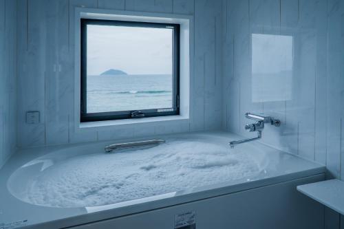 a bathroom with a bath tub with a window at THE SHIKAKA Hotel&Resort BUDOUNOKI in Itoshima