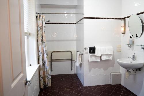 a white bathroom with a sink and a shower at Heritage On Horseshoe Guest House in South West Rocks